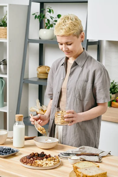 Zdravá mladá žena připravuje müsli k snídani — Stock fotografie