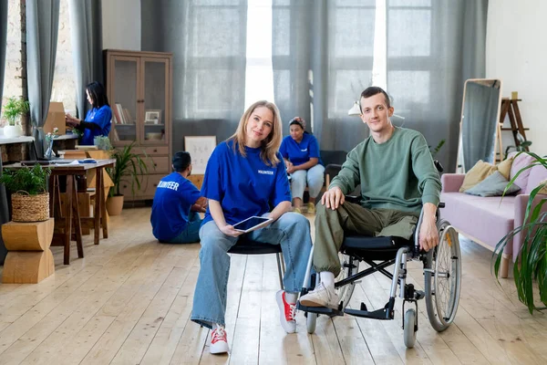 Jong blond vrouw zitten door handicap guy in rolstoel — Stockfoto