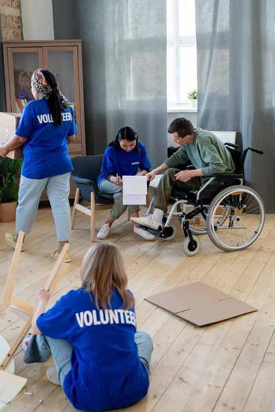 Groep vrijwilligers werkzaam in appartement van gehandicapte man — Stockfoto