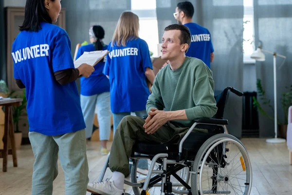 Gehandicapte man in rolstoel in gesprek met een van de vrijwilligers — Stockfoto