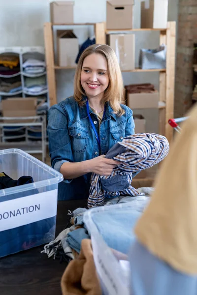 Молодая блондинка выбирает одежду для пожертвований — стоковое фото