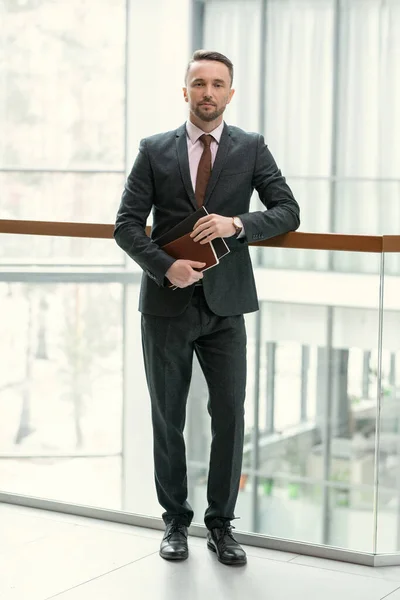 Uomo d'affari con cartelle in piedi in ufficio — Foto Stock