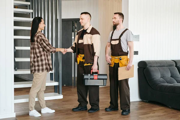 One of two repairmen shaking hand of female client — Stock Photo, Image