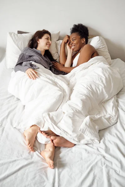 Lésbicas casal deitado na cama sob cobertores brancos — Fotografia de Stock