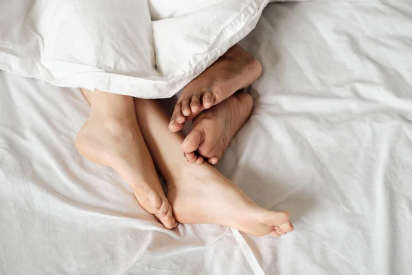 Pés nus de mulheres multirraciais deitadas na cama — Fotografia de Stock