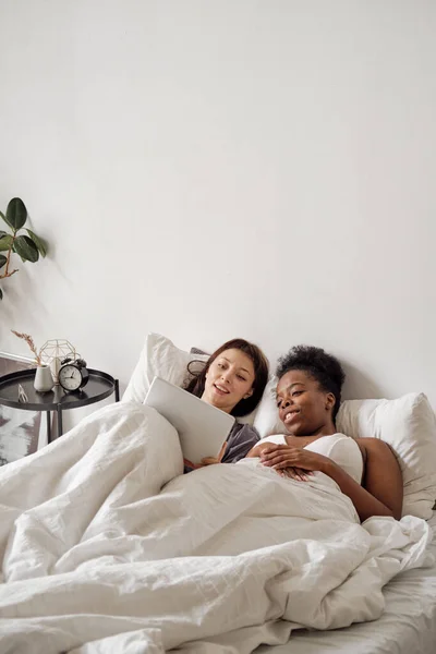 Two young women with tablet relaxing in bed — Stock Photo, Image