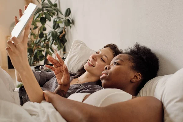 예쁜 레즈비언 여자들 이 침대에서 비디오 채팅으로 얘기하는 모습 — 스톡 사진