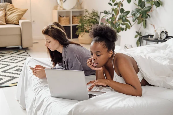 Jóvenes hembras usando aparatos móviles en la cama — Foto de Stock