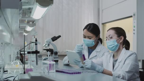 Beyaz Önlüklü Yüz Maskeli Kadın Kimyagerler Test Tüpünde Mor Çözeltiyi — Stok video