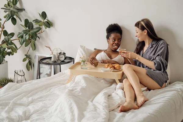 Zwei glückliche Mädchen frühstücken im Bett — Stockfoto