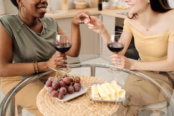 Две счастливые девушки пьют красное вино за столом — стоковое фото