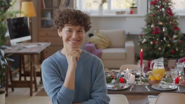 거실에서 카메라 앞에서 곱슬머리로 여성의 맛있는 장식된 크리스마스 트리를 배경으로 — 비디오