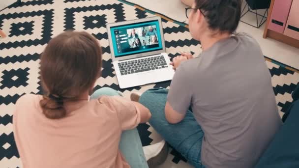 年轻女子坐在地板上 通过笔记本电脑上的视频通话与一群人交谈的高角度慢镜头 — 图库视频影像