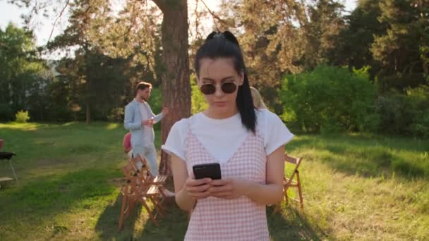 Modern Beyaz Bir Kadının Parkta Akıllı Telefonuyla Bir Şeyler Izlerken — Stok video