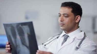 Orta ölçekli bir portre, hastanede çalışan Orta Doğulu genç bir adamın kameraya bakarken röntgen görüntüsü.