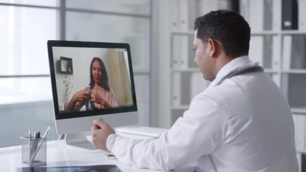 Arzt Sitzt Schreibtisch Vor Computermonitor Und Beobachtet Seine Patientin Bei — Stockvideo