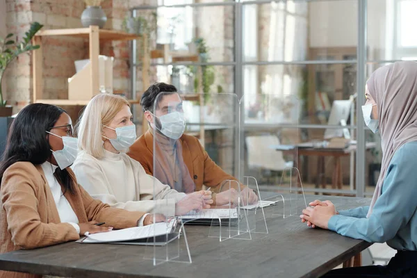 마스크를 쓴 여러 인종의 고용주들 이 히잡을 쓴 젊은 여성을 보고 있다 — 스톡 사진