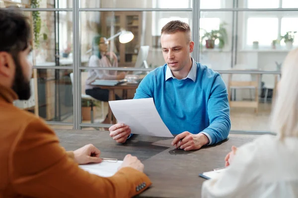 Giovane candidato serio guardando attraverso la carta di fronte ai datori di lavoro — Foto Stock