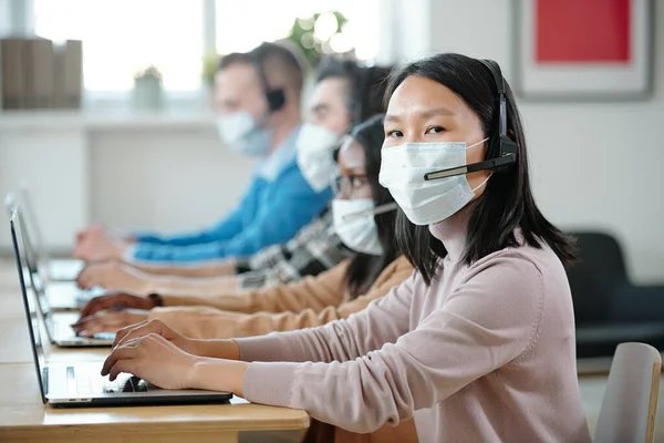 Jong aziatisch operator in beschermende masker kijken naar camera — Stockfoto