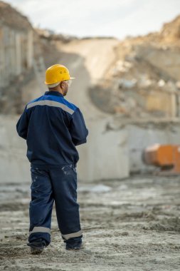 Çağdaş taş ocağı işçisinin üniformalı ve şapkalı arka görünüşü