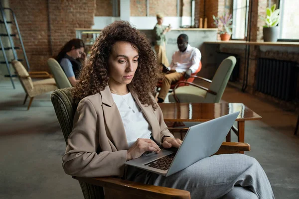 Joven mujer de negocios usando el ordenador portátil mientras está sentado en el sillón —  Fotos de Stock
