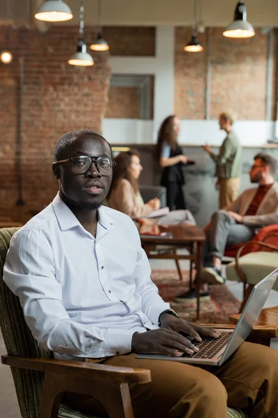 Young businessman working in the net while his colleagues discussing working points — Stock Photo, Image