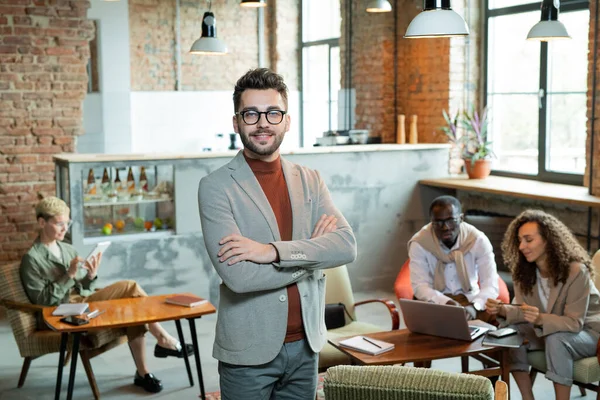 Young smiling businessman standing in front of working colleagues — Stock Photo, Image