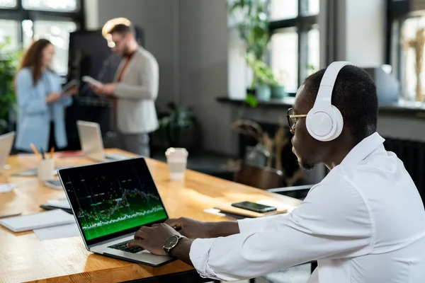 Afrykański ekonomista w słuchawkach za pomocą laptopa — Zdjęcie stockowe
