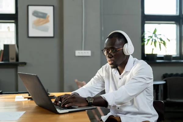 Jonge witte boorden werknemer in hoofdtelefoon werken met online gegevens — Stockfoto