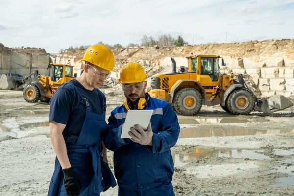 Dos constructores en ropa de trabajo mirando boceto en la pantalla de la tableta —  Fotos de Stock