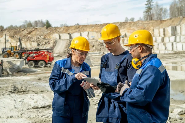 Drei interkulturelle Baumeister schauen auf Tablet-Display — Stockfoto