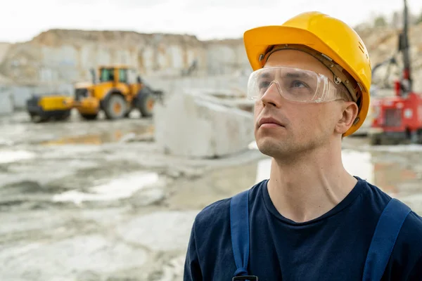 Young serious businessman in hardhat standing at building place — Stock Photo, Image