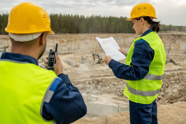 Ingegnere donna guardando schizzo e la sua collega utilizzando walkie-talkie — Foto Stock