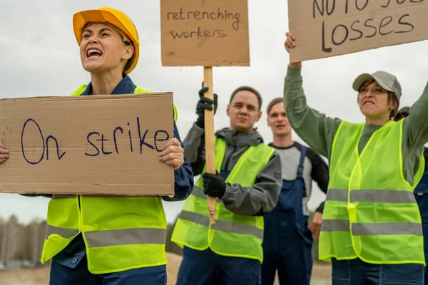 Группа сотрудников в рабочей одежде носит плакаты во время забастовки — стоковое фото