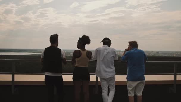 屋上に立って街並を眺める若い男女のドリーインリアビュー — ストック動画