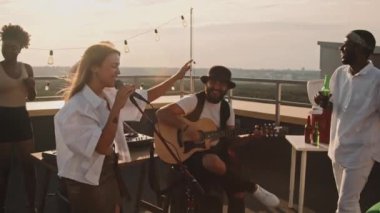 Güzel bir yaz akşamında çatıdaki terasta şarkı söyleyen müzisyenlerin yavaşlığı