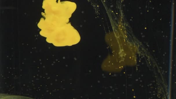 遅い黄色の塗料のショットを閉じると暗い背景に水の中で渦巻く — ストック動画