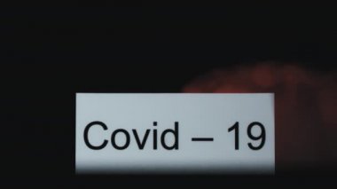 Kelime Covid-19 ile çevreleyen kırmızı duman perdesinin yavaş çekimini kapat