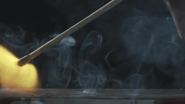Kişiyi kameradan uzaklaştırıp kibriti çakarken yakın çekim yap ve ateşle.