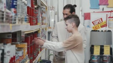 Hırdavatçıdan boya alan genç adam ve gencin yavaş yavaş aşağı eğilmesi.