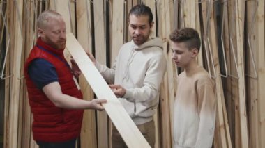 Erkek evlerinin yavaş gelişimi. Kabarık yelek giyen mağaza çalışanı. Baba ve oğlunun yan panel seçmesine yardım ediyor.
