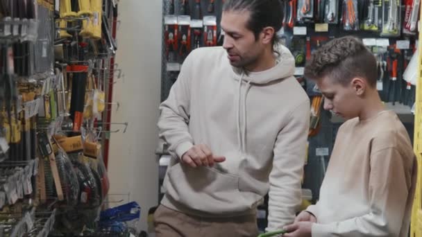 Alışveriş Arabalı Bir Adam Çocuğun Nalbur Dükkanındaki Çeşitli Geliştirme Malzemelerini — Stok video