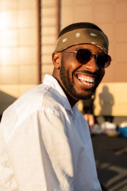 Beyaz gömlekli neşeli Afrikalı adam kameranın önünde duruyor.