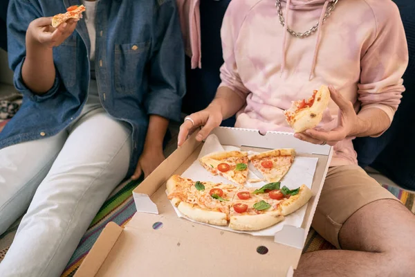 Два подростка в повседневной одежде едят пиццу, сидя на полу — стоковое фото