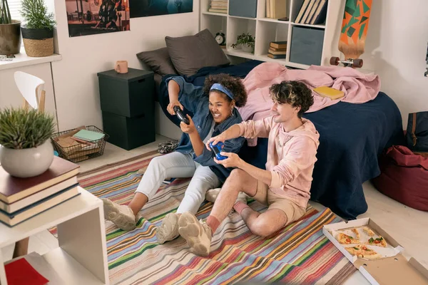 Samtida tonåringar som sitter på golvet och spelar tv-spel — Stockfoto