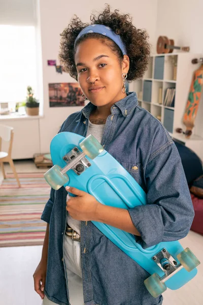 Glücklicher afrikanischer Teenager in Freizeitkleidung mit blauem Skateboard — Stockfoto