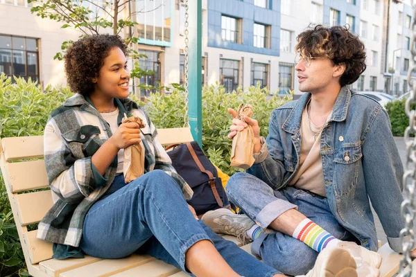 Unga interkulturella par i fritidskläder som dricker utomhus — Stockfoto