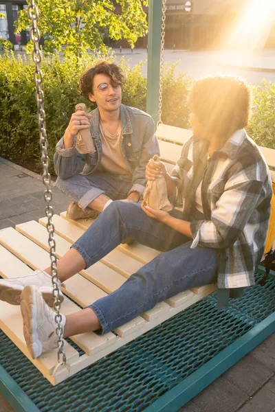 Dos amigos casuales con botellas envueltas en papel tomando bebidas al aire libre —  Fotos de Stock