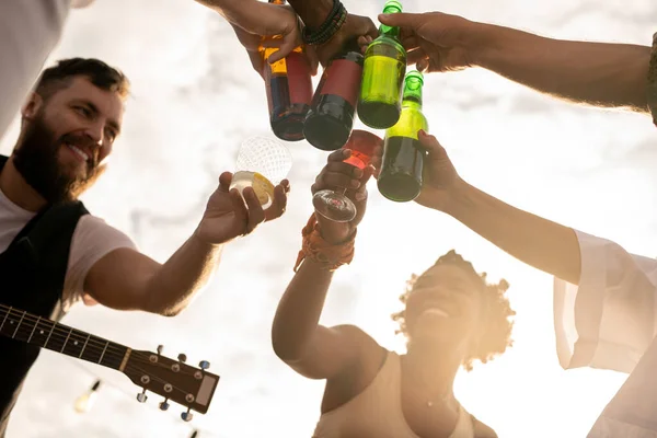Hände junger Freunde stoßen mit Getränken im Freien an — Stockfoto