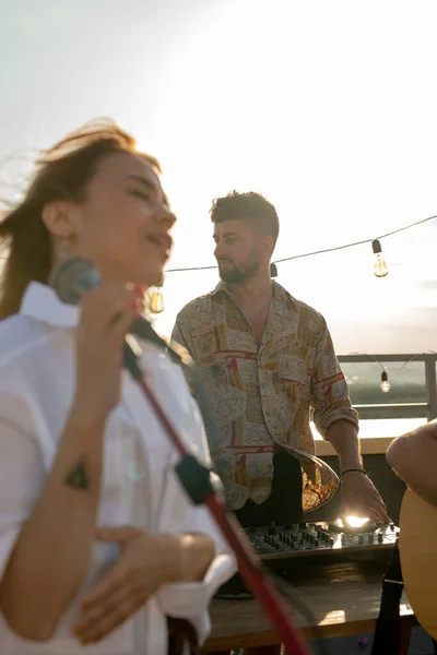 Young man standing by soundboard during rooftop party — Stock Photo, Image